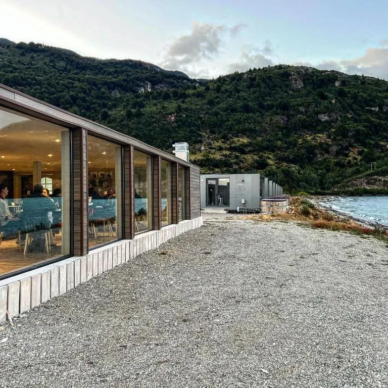 Fachada del RestoBar con ventanales y las cabañas al fondo, junto al lago